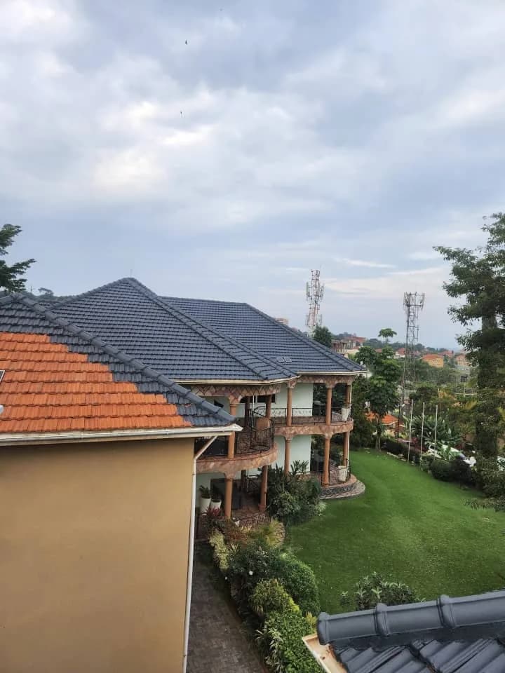 Residential roof half-painted charcoal grey over terracotta tiles
